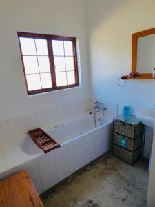 Baño blanco con bañera y lavamanos en Bamboo Mountain Farm en Underberg