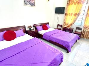 2 camas en una habitación con sábanas moradas y almohadas rojas en Gia Hoang Hotel, en Quy Nhon