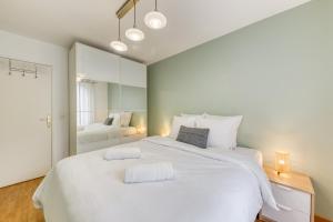 una camera da letto con un grande letto bianco e uno specchio di Lumineux 3 pièces Paris / Disney a Champs-Sur-Marne