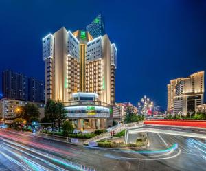 Holiday Inn Kunming City Centre, an IHG Hotel في كونمينغ: مبنى كبير في وسط المدينة ليلا