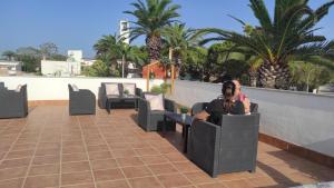 two people sitting in chairs on a patio with palm trees at Alojamiento Lo Trabucador in El Poblenou del Delta