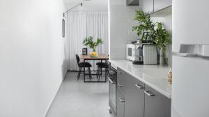 a kitchen with white appliances and a table with chairs at דירת סטודיו מרווחת במתחם סי סייד עם חניה פרטית -By Edomlux in Eilat