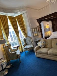 een slaapkamer met een bed, een bank en een stoel bij Blue Sky Guest House in Brighton & Hove