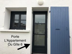 un bâtiment blanc avec une porte bleue et un panneau dans l'établissement Clos des Aigrettes, La Cotinière, à La Cotinière