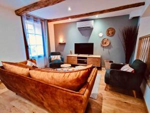 Gîte de l’Ancien Puits في Saint-Bauzille-de-la-Sylve: غرفة معيشة مع أريكة كبيرة وتلفزيون