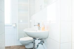 a white bathroom with a sink and a toilet at Hostel & Hotel Braunlage in Braunlage