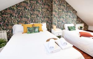 2 camas en una habitación con papel pintado floral en CASA COMPLETA EN SANTIAGO, HASTA 9 HUÉSPEDES, en Santiago de Compostela