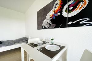 a white dining room with a table and a painting on the wall at Nice Appartement in Trappenkamp in Trappenkamp