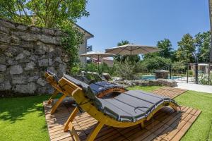 a deck with a chaise lounges and an umbrella at Luxury Kvarner Park Villa with garden and large RGB private pool in Kastav