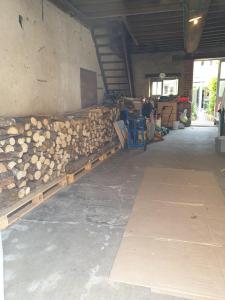 Ein Haufen Holz in einem Gebäude mit Menschen im Hintergrund in der Unterkunft Les Géraniums Sullylois in Sully-sur-Loire