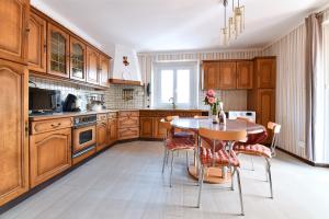una cocina con armarios de madera y una mesa con sillas. en Gite des Hirondelles en Ostheim