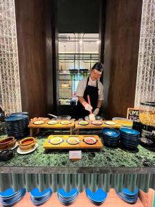 a man standing in a kitchen preparing food at Herloom Hotel & Residence BSD Tangerang in Tangerang