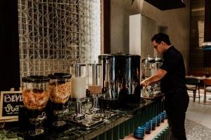 a man standing in front of a counter with a counter at Herloom Hotel & Residence BSD Tangerang in Tangerang