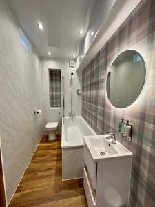 a bathroom with a sink and a tub and a mirror at 4 Sheraton Apartments in Fort William