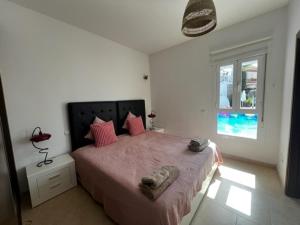 1 dormitorio con cama con sábanas rosas y ventana en Duende Marbella, en Marbella
