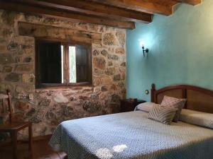 佩拉萊霍斯德拉斯特魯查斯的住宿－Acebos del Tajo，一间卧室设有一张床和石墙