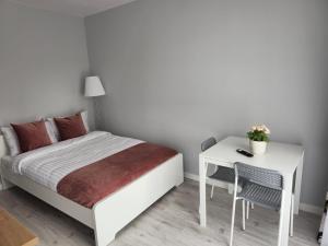 a bedroom with a white bed and a desk at Willa Impresja in Gdańsk