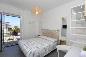 a white bedroom with a bed and a balcony at Luna Calante in Santa Maria di Castellabate
