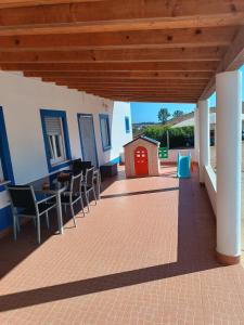 a covered patio with chairs and a red door at Casa do Chaparral campo e praia in Cercal