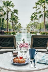 a table with a plate of pastries and a cup of coffee at Kanvaz Village Resort Seminyak in Seminyak