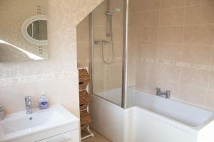 uma casa de banho com um chuveiro, uma banheira e um lavatório. em Longfield, Daviot em Inverness