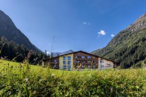 un edificio en una colina con montañas en el fondo en Hotel Sonnblick, en Sankt Leonhard im Pitztal