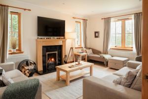 a living room with a fireplace and a tv at Balnagowan Cottage in Nethy Bridge