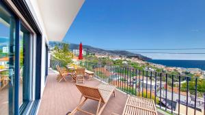 een balkon met stoelen en tafels en uitzicht op de oceaan bij Costa Vista by LovelyStay in Funchal