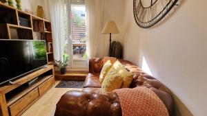 un sofá de cuero marrón en una sala de estar con TV en Àtic Trobador, en Barcelona
