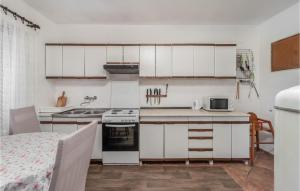 uma cozinha com armários brancos e um forno com placa de fogão em Gorgeous Apartment In Lopar With Wifi em Lopar