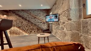 sala de estar con TV en una pared de piedra en CASA MEIGO, en Chantada