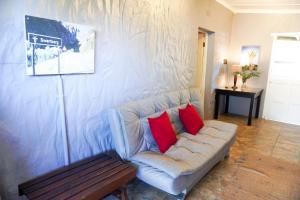 a living room with a couch with two red pillows at AVONDBLIJ Apartment in Oudtshoorn