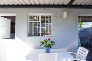 a white table with a vase of flowers on it at AVONDBLIJ Apartment in Oudtshoorn