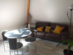 salon z kanapą, stołem i żółtymi poduszkami w obiekcie logies 'Raapbreuk' w mieście Herentals