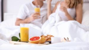 a couple in bed with a tray of food and orange juice at Luxury living 100 meter from the beach - by Edom in Eilat