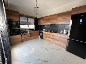 a large kitchen with wooden cabinets and a black refrigerator at New Sea View Flat in Long Beach in Perivolia tou Trikomou