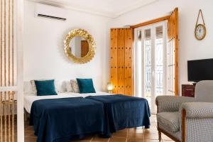 a bedroom with a bed with blue sheets and a mirror at Placentines in Seville