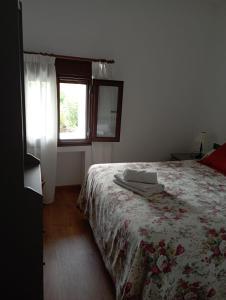 Un dormitorio con una cama con una manta de flores y una ventana en Casa rural La Barriada de Lago de Carucedo, en Lago de Carucedo