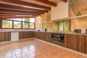 a large kitchen with wooden cabinets and a microwave at Finca Can Setri in Sant Llorenç des Cardassar