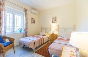 a bedroom with two beds and a chair and a window at La Nuestra CaRo in Salobreña +9 photos