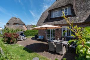 a patio with an umbrella and a table and chairs at Gelys Huus in Midlum
