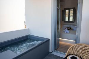 a room with a tub with a bed in the background at Aidani Luxurious Rooms in Vóthon