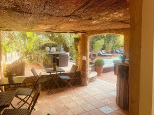 a patio with a table and chairs and a pool at Le Mas d'Olivier in Le Plan-de-la-Tour