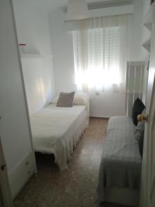 een witte kamer met 2 bedden en een raam bij Edificio tarifa playa in Tarifa
