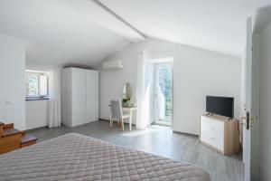 a white bedroom with a bed and a tv at Casale del Nonno in Sorrento