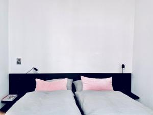 a bedroom with two beds with pink and white pillows at zehuus - historical charm 70qm in Cologne