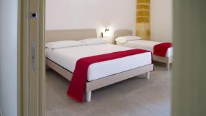1 dormitorio con 2 camas y manta roja en Perla Suite, en Mesagne