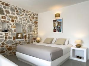 um quarto com uma cama e uma parede de pedra em Sirocos em Karavostasi