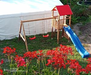 a playground with a slide and red flowers at Willa Epiona in Stepnica