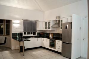 una cucina con armadi bianchi e frigorifero in acciaio inossidabile di EL Paraiso a La Pared